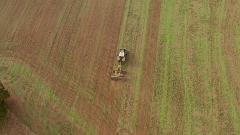 Pan-up-aerial-shot-of-a-tractor-ploughing-a-field