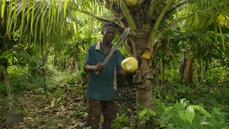 Schwarzafrikanischer-Mann-Schneidet-Eine-Kokosnuss-In-Einem-Dschungel-Regenwald-Mit-Einer-Großen-Messermachete