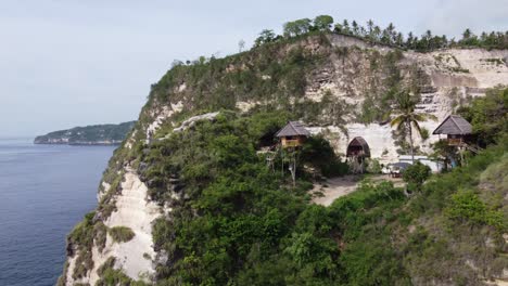 Rumah-Pohon-treehouse-Huts-on-oceanside-cliff-in-Nusa-Penida,-Aerial