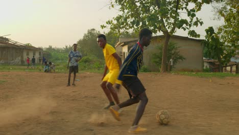 Young-football-player-dribbles-the-ball-through-boys-wearing-jerseys-yellow-and-blue-then-kicks-it-towards-the-goal,-goal-keeper-stops-it-from-scoring,-community-football-pitch,-Kumasi,-Ghana
