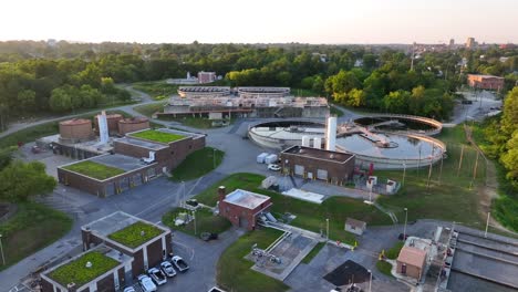 Aerial-shot-capturing-the-layout-of-a-wastewater-treatment-facility-at-dusk,-with-circular-clarifiers-and-green-roofed-buildings