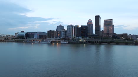 Aerial-over-Ohio-River-looking-towards-downtown-Louisville,-Kentucky-skyline-during-sunrise