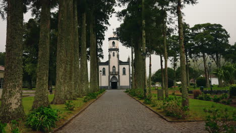 Walking-through-the-pathway-toward-the-front-view-of-local-small-church-facade-located-on-Sao-Miguel-Island,-Azores