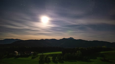 Stars-twinkle-as-night-clouds-drift-over-Attersee-Lake-hills,-captured-in-a-nocturnal-timelapse