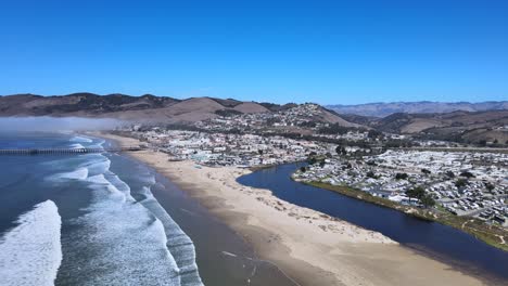 Soar-above-Pismo-Beach,-capturing-the-stunning-ocean-views-and-majestic-mountains-in-the-background-with-this-breathtaking-aerial-drone-footage