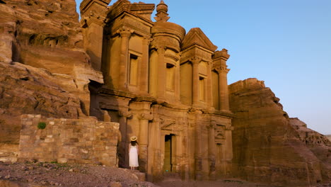 Woman-Standing-And-Looking-At-Ancient-Facade-Of-Ad-Deir-Monastery-In-Petra,-Jordan-At-Sunset