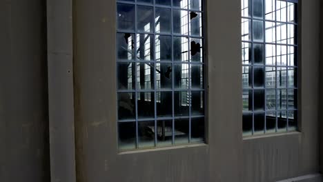 Looking-through-long-Art-Deco-windows-of-abandoned-disused-derelict-power-station-factory-warehouse-in-East-Perth,-View-is-through-to-the-outside-as-we-ascend