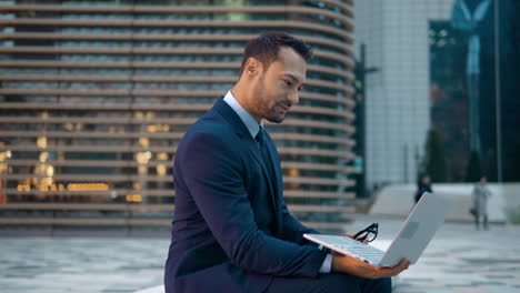 Businessman-outside-office-building-reading-messages-on-laptop
