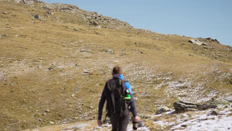 Un-Excursionista-Masculino-Solitario-Caminando-Por-El-Sendero-Con-Una-Panorámica-Hacia-Arriba-Para-Revelar-A-Ambos-En-La-Cima-De-La-Montaña-En-Valmalenco.
