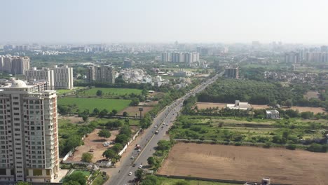 RAJKOT-CITY-AERIAL-VIEW-DRONE-CAMERA-FROM-SIDE-ANGLE-OF-KALAVAD-ROAD-MANY-PARTY-PLOTS-AND-LARGE-FIELDS-WITH-MANY-VEHICLES-ON-THE-ROAD