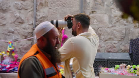 Fotógrafo-Con-Cámara-Profesional-Tomando-Fotografías-En-La-Concurrida-Calle-Con-Un-Transeúnte-En-Jerusalén,-Israel
