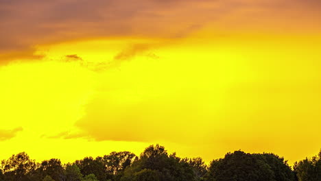 A-View-Of-A-Golden-Dramatic-Sky-With-Colourful-Clouds-Moving-Horizontally-Above-A-Green-Forest
