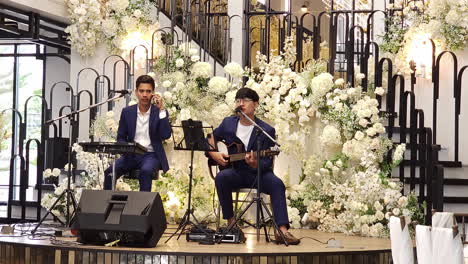 Wedding-entertainers,-a-drummer,-guitarist,-and-vocalists-are-entertaining-guests-at-a-wedding-reception-in-a-restaurant-in-Bangkok,-Thailand