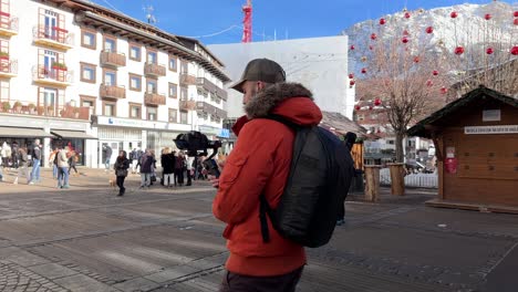 Cortina-d'Ampezzo-cityscape-in-Italy-and-videographer-walking-while-holding-camera-mounted-on-stabilizing-gimbal-DJI-RS3-Mini