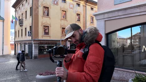 Professional-videographer-setting-camera-mounted-on-stabilizing-gimbal-DJI-RS3-Mini,-Cortina-d'Ampezzo-in-Italy