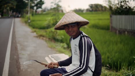 Asian-Rice-Farmer-In-Lombok,-Indonesia-Waits-For-The-Bus-After-Harvesting-In-The-Rice-Fields