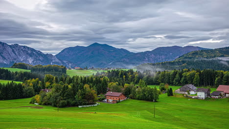 Mist-and-moody-cloud-move-over-lush-rural-Attersee-village-landscape,-time-lapse