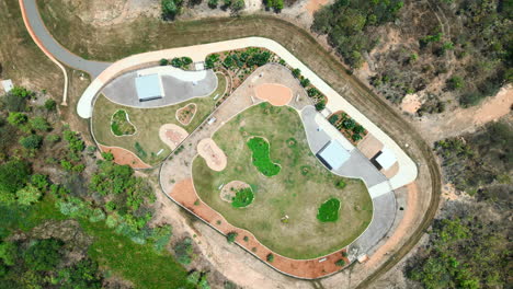 Modern-dog-park,-with-vibrant-lush-grass,-neatly-arranged-gravel-garden-beds,-concrete-walkways-and-shaded-seating-areas