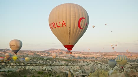 Türkische-Heißluftballons-Fliegen-über-Eine-Wunderschöne-Morgendliche-Raue-Landschaft