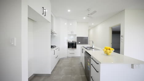 Modern-sleek-open-plan-all-white-kitchen-with,-gas-cooktops,-and-stainless-steel-appliances