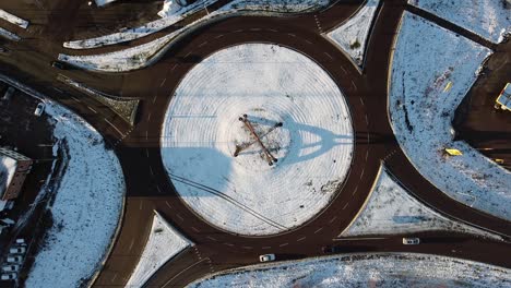 Bird's-eye-view-above-snow-covered-round-about-traffic-circle-at-midday,-long-shadows-cast-on-snow