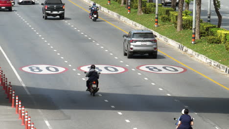 Cars-and-taxis,-motorcycles-and-vans,-moving-forward-with-the-pavement-marked-with-maximum-speed-of-80-km-per-hour,-Bangkok,-Thailand