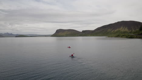 Hestvik-lake-and-landscape-aerials-in-Iceland-following-to-kayaks-as-they-head-off-into-the-distance