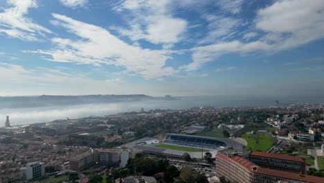 Daytime-aerial-of-city-dwelling-residential-area-with-soccer-stadium-facility,-ocean-water-surface-visible-in-distance,-location-Portugal