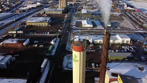 Smoke-emits-from-smokestack-pipe-in-industrial-factory-area-of-snowy-Scandinavian-town