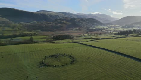 Ancient-stone-circle-in-field-with-orbit-revealing-mountains-and-misty-valley-on-autumn-morning-at-Castlerigg-Stone-Circle,-English-Lake-District-National-Park,-Cumbria,-UK