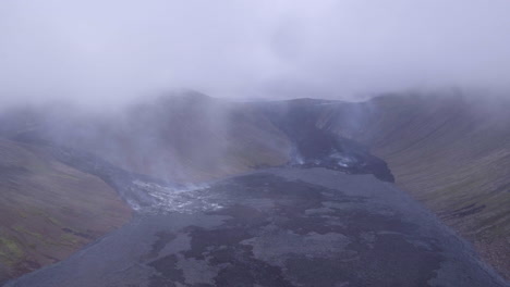 Fagradalsfjall-volcano-in-Iceland-aerial-pull-back-shot-through-the-clouds-and-rising-steam-on-a-winters-day