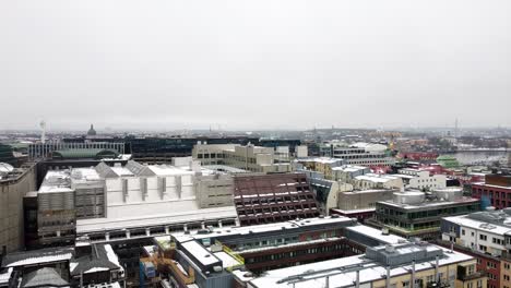 Drone-ascend-tilt-down-to-reveal-industrial-apartment-and-offices-with-snow-on-roofs-on-grey-cloudy-day