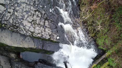 A-top-down-shot-of-a-waterfall,-tracking-the-river-as-it-goes-over-the-falls