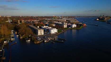 Amsterdam-Noord-IJplein-drone-fixed-shot-next-river-with-boat-arriving