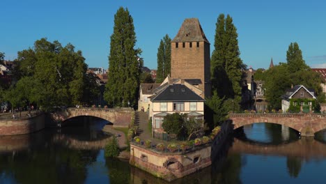 Der-Fluss-Ill-Fließt-In-Der-Nähe-Der-Türme-Ponts-Couverts-Im-Bezirk-La-Petite-France-An-Einem-Gemütlichen-Abend-Zur-Goldenen-Stunde-In-Der-Stadt-Straßburg