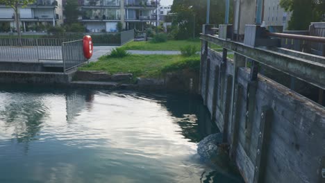 Interlaken-Immersive-POV:-Bewegung-Durch-Die-Straßen-Der-Stadt-Am-Frühen-Morgen-In-Der-Schweiz,-In-Europa,-Zu-Fuß-|-Zitternde-Bewegung-Von-Der-Kleinen-Brücke-Zu-Den-Häusern-Am-Türkisfarbenen-Wasser