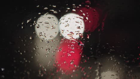 A-close-up-of-raindrops-on-the-glass-behind-which-the-lights-of-passing-cars-create-a-colourful-atmosphere-of-night-traffic