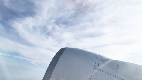 Airplane-wing-cruising-above-wispy-clouds-in-blue-sky