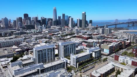 High-definition-drone-video-capturing-the-dynamic-skyline-of-downtown-San-Francisco,-featuring-the-Salesforce-Tower,-Transamerica-Pyramid,-and-the-Bay-Bridge-against-a-clear-blue-sky