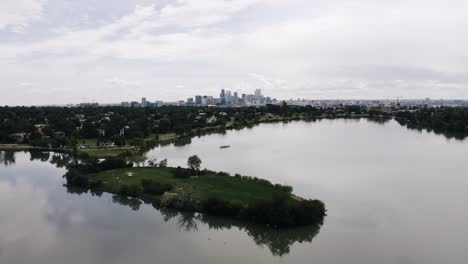 Drone-shot-pushing-over-Sloan-Lake-towards-Denver's-downtown-skyscrapers