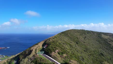 Drone-ascends-above-green-trees-of-Monte-da-Guia-revealing-Pico-Island