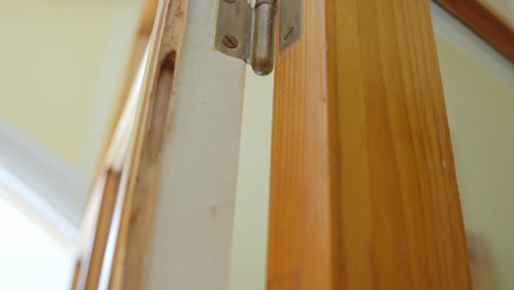 Closeup-view-at-metallic-hinges-holding-brown-door-chewed-by-termites