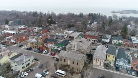 A-drone-captures-an-aerial-view-of-Niagara-on-the-Lake's-downtown-courthouse,-slowing-zooming-out-on-the-surrounding-historical-buildings-on-a-wintery-day-while-snow-lightly-falls