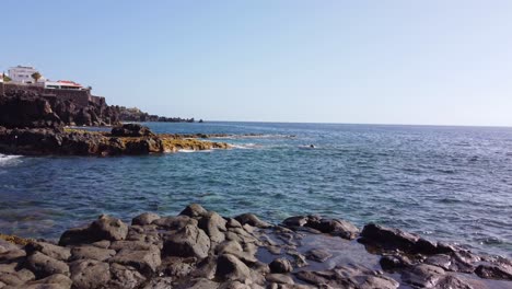 View-at-coastal-town,-endless-ocean-surface-surrounding-rocky-shore