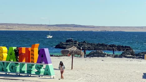 People-at-the-Bahia-Inglesa-sign-and-beach,-sunny-day-in-Coquimbo-region,-Chile