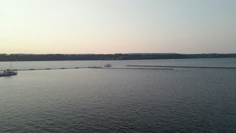 Sonnenuntergang-Am-Ontariosee,-Während-Das-Weite,-Blaue-Wasser-Kräuselt-Und-Eine-Weiße-Yacht-Links-Vom-Bild-Fährt-Und-Eine-Kleine-Spur-Auf-Ihrem-Weg-Hinterlässt
