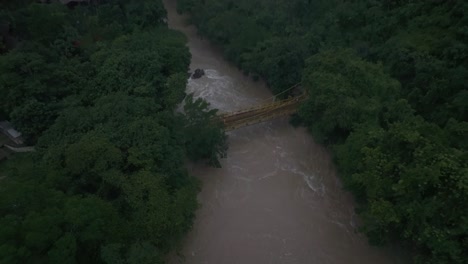 Drone-view-of-yellow-bridge-crosses-the-cahabon-river-at-Semuc-champey,-aerial