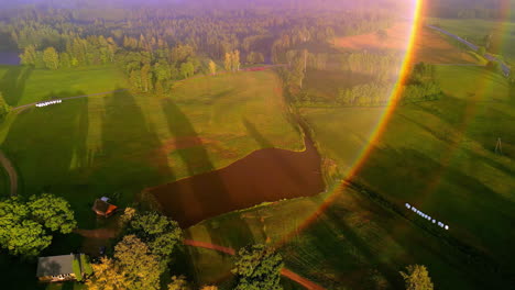 Bird's-eye-view-over-a-green-landscape-with-lakes,-sun-flares-in-the-lens