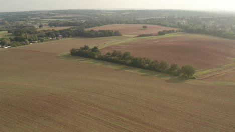 Wide-aerial-shot-over-an-expanse-of-ploughed-fields-in-the-english-countryside