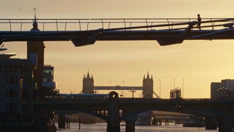 Pedestrian-jogging-across-the-Millennium-Bridge-in-early-morning-in-London,-United-Kingdom